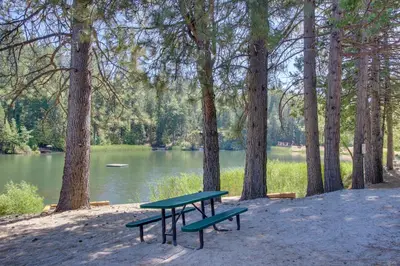 a picnic table and two benches in front of a lake at Paws Place in Arnold