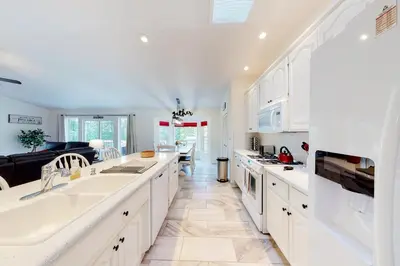 a kitchen with white cabinets and a living room at The 19th Hole in Groveland