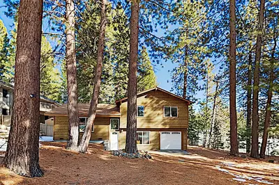 a wooden house with a garage in the woods at Allen Way Escape in Incline Village