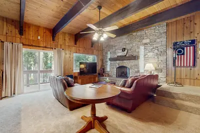 a living room with a table and a stone fireplace at Conifer Donner in Truckee