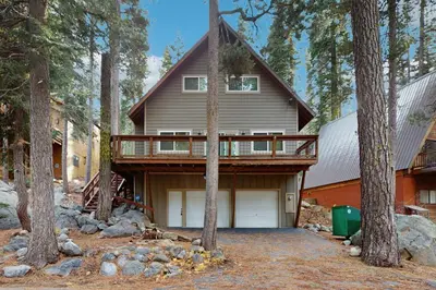 a house in the woods with a balcony on it at Conifer Donner in Truckee