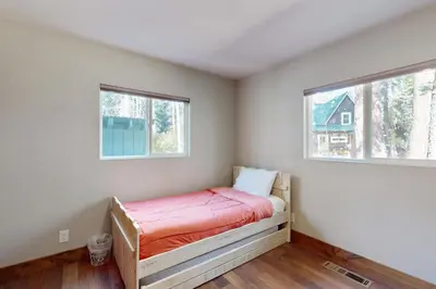 a bedroom with a bed and two windows at Homewood Cabin Among the Pines in Homewood