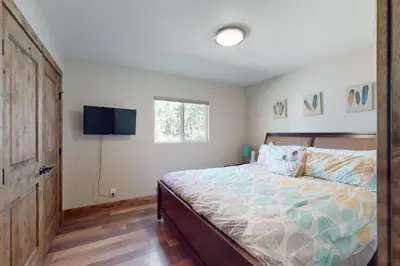 a bedroom with a bed and a flat screen tv at Homewood Cabin Among the Pines in Homewood