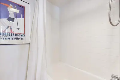 a bathroom with a white shower curtain and a poster at Alpine Haven in Tahoe City