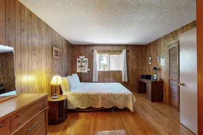 a bedroom with a bed and a window and wooden walls at Pineland Escape in Tahoe City