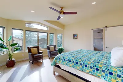 a bedroom with a bed and two chairs and a ceiling fan at Tahoe Keys Haven in South Lake Tahoe
