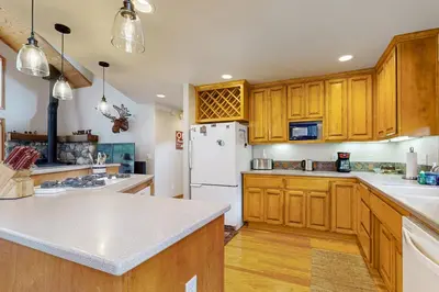 a kitchen with wooden cabinets and a white refrigerator at Tahoe Donner Snow Globe in Truckee