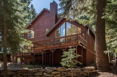 a house in the woods with a wrap around deck at Tahoe Donner Snow Globe in Truckee