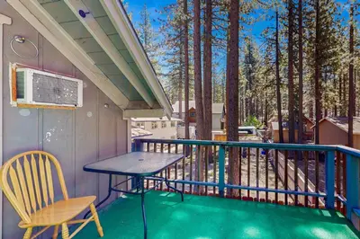 a table and a chair on a balcony with trees at Hank Monk Manor in South Lake Tahoe