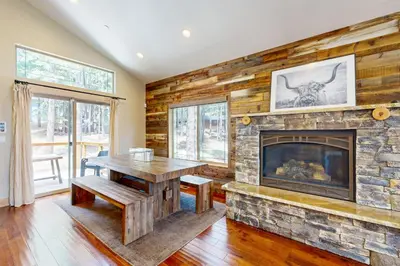 a living room with a stone fireplace and a table at Luxury Mountain Retreat in South Lake Tahoe