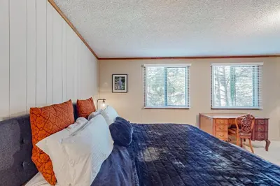 a bedroom with a bed and a desk and two windows at Sky Meadows Charmer in South Lake Tahoe