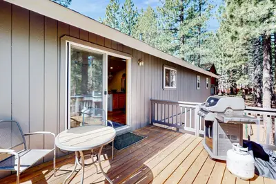 a deck with a table and chairs on a house at Sunlit Forest Haven in South Lake Tahoe