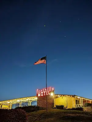 a flag flying in front of a building with a sign at Foothills Motel in Auburn