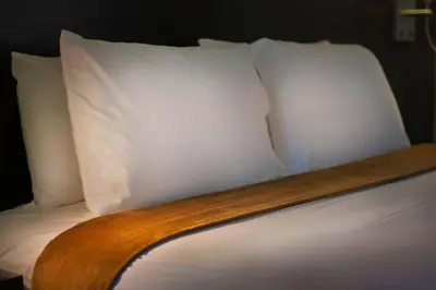 a bed with white pillows on top of it at Foothills Motel in Auburn