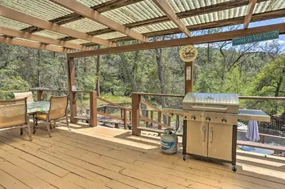 a patio with a grill and a table on a deck at Gorgeous Oakhurst Retreat with Swimming Hole! in Oakhurst