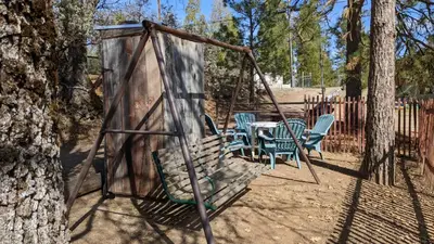 a swing set in a yard with chairs and a table at Room #3 at the Apple Place in Miramonte