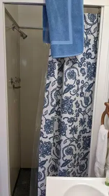 a bathroom with a shower with a blue and white shower curtain at The Apple Place Room #2 in Miramonte