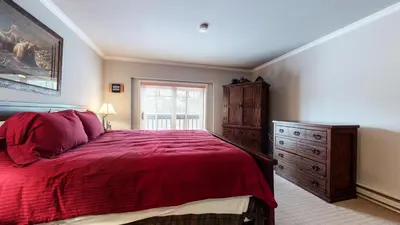 a bedroom with a red bed with a dresser and a window at Mammoth Green #205 condo in Mammoth Lakes