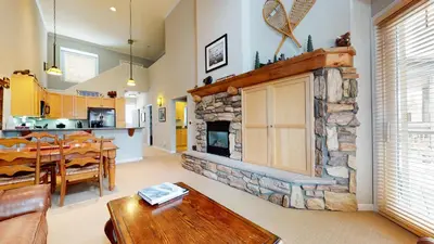 a living room with a stone fireplace and a table at Mammoth Green #205 condo in Mammoth Lakes