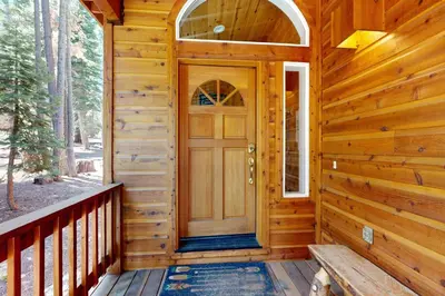 a wooden front door of a cabin with a bench at Tyrol Getaway in Truckee