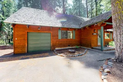 a log cabin with a garage door in the woods at Tahoe Pines Cabin in Homewood