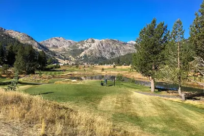 a golf course with a pond and mountains in the background at Resort at Squaw Creek's 560 & 558 in Olympic Valley