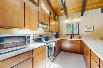 a large kitchen with wooden cabinets and a microwave at Simplon Pass Escape in Homewood