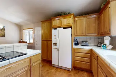 a white refrigerator in a kitchen with wooden cabinets at High Meadow Storybook in South Lake Tahoe