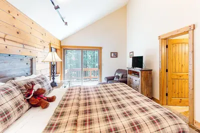 a teddy bear sitting on a bed in a bedroom at The Bear's Lair House in Truckee