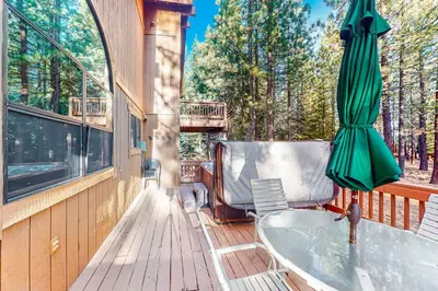 a deck with a bath tub and a umbrella at The Bear's Lair House in Truckee