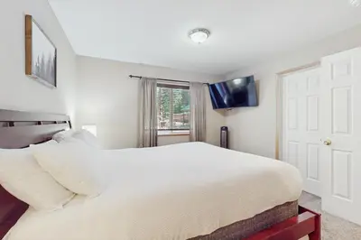 a bedroom with a white bed and a tv on the wall at Backyard Oasis in South Lake Tahoe