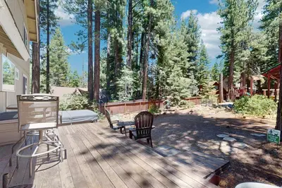 a deck with a bench and a grill and trees at Backyard Oasis in South Lake Tahoe