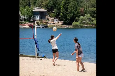 two women playing a game of volleyball on the beach at New Luxury 5BR Cabin in Pine Mountain Lake! 1 Minute to Beach! Massage Chair! Close to Yosemite! Perfect for Retreats and Escapes All Seasons! in Groveland