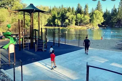 a man and two children playing at a playground at New Luxury 5BR Cabin in Pine Mountain Lake! 1 Minute to Beach! Massage Chair! Close to Yosemite! Perfect for Retreats and Escapes All Seasons! in Groveland