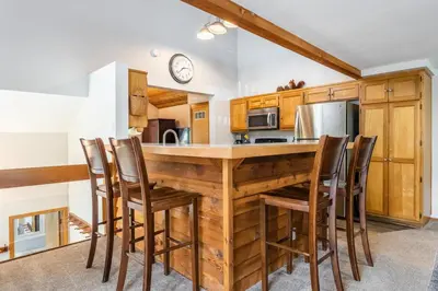 a kitchen with a wooden counter with chairs around it at Snowcreek IV 549 in Mammoth Lakes