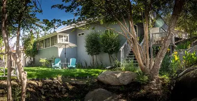 a house with two chairs and an umbrella in the yard at Birdwatch Cottage With River Beach Pass in Three Rivers