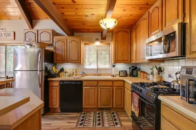 a kitchen with wooden cabinets and a stainless steel refrigerator at Furnished Deck High Sierra Cabin in Twain Harte! in Twain Harte