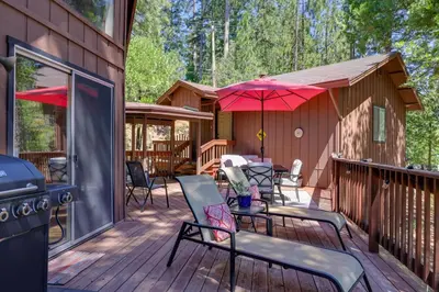 a deck with chairs and umbrellas on a cabin at Furnished Deck High Sierra Cabin in Twain Harte! in Twain Harte