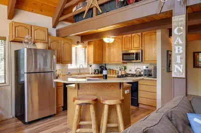 a kitchen with wooden cabinets and a stainless steel refrigerator at Furnished Deck High Sierra Cabin in Twain Harte! in Twain Harte
