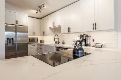 a kitchen with white cabinets and a stainless steel refrigerator at Chamonix 24 is a 2bed plus loft 3 bath Upgraded Canyon Ldge Nearly Ski in Ski Out Sleeps 8 in Mammoth Lakes