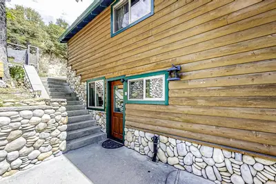 a house with a stone wall and a wooden door at Lakefront Retreat in Bass Lake