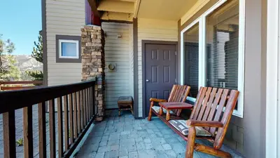 two wooden chairs sitting on the front porch of a house at Eagle Run #114 condo in Mammoth Lakes