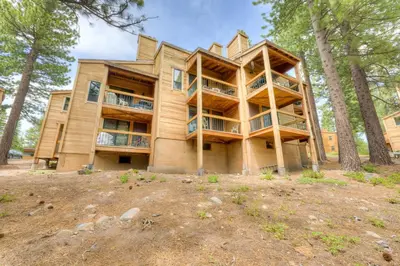 a large wooden building with balconies in the woods at Pine Time in Truckee