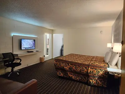 a hotel room with a bed and a flat screen tv at Holiday Lodge in Hawthorne