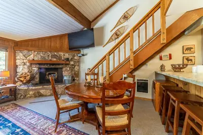 a dining room with a wooden table and a stone fireplace at Mountainback 100 in Mammoth Lakes