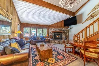 a living room with a couch and a table and a fireplace at Mountainback 100 in Mammoth Lakes