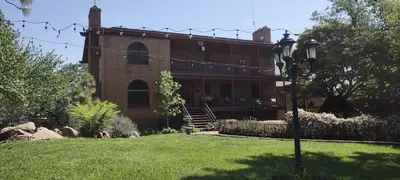 a large brick house with a porch and a yard at Rustic Rooms by Kings Canyon & Sequoia National Parks in Squaw Valley