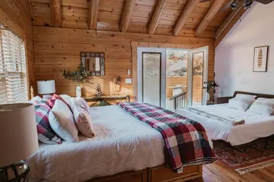 two beds in a room with wooden walls at Scenic View Timber Lodge HotTub by Casa Oso in Mariposa