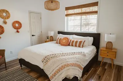 a bedroom with a bed with orange pillows and a window at Sunset Glow Hidden Meadow BBQ HotTub by Casa Oso in Oakhurst