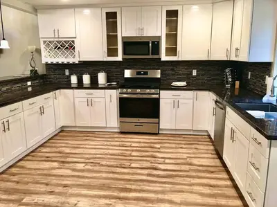 a kitchen with white cabinets and a wooden floor at Modern Cabin Get Away - close to APPLE HILL in Pollock Pines